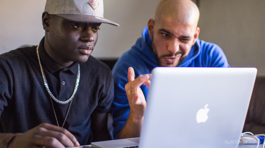 Rapper Danny Fresh rechts im Bild mit einem Workshop Teilnehmer feilen am Song vor einem Laptop.